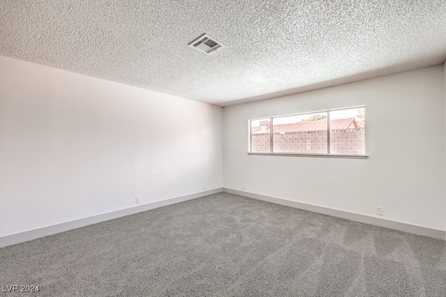 carpeted empty room featuring a textured ceiling