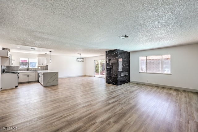 unfurnished living room featuring light wood-type flooring, a textured ceiling, and sink