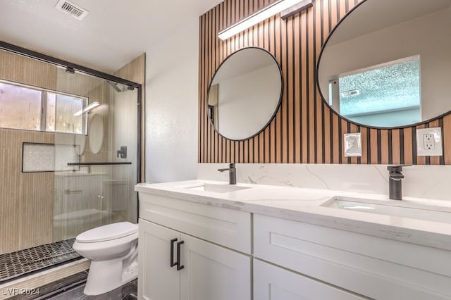 bathroom featuring a shower with shower door, vanity, and toilet