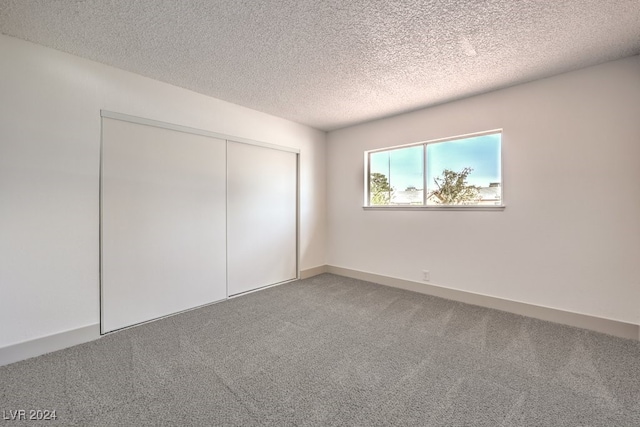 unfurnished bedroom with a textured ceiling, a closet, and carpet