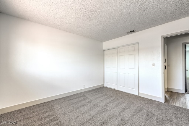 unfurnished bedroom featuring a textured ceiling, a closet, and carpet floors