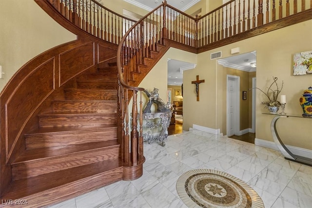 stairs with ornamental molding and a towering ceiling