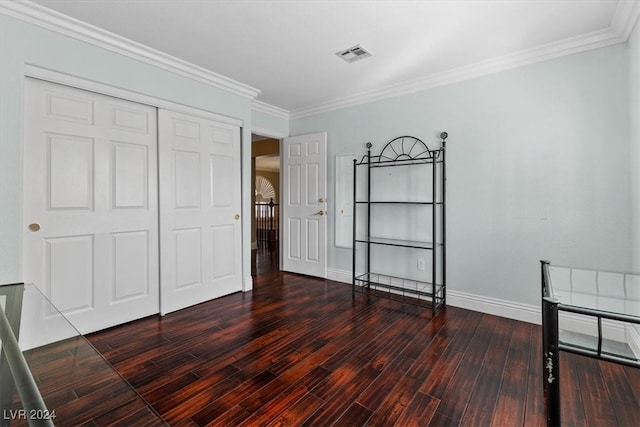 unfurnished bedroom featuring crown molding, dark hardwood / wood-style floors, and a closet