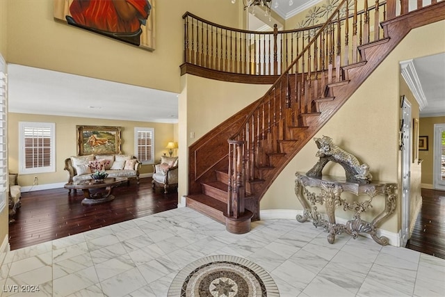 stairway featuring a towering ceiling, wood-type flooring, and ornamental molding