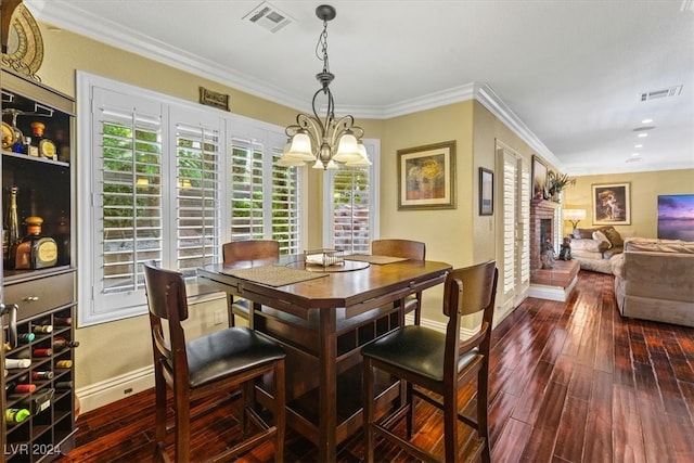 dining area featuring hardwood / wood-style floors, a fireplace, a chandelier, and ornamental molding