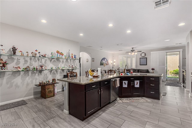 kitchen featuring light stone counters, ceiling fan, dishwasher, and a wealth of natural light