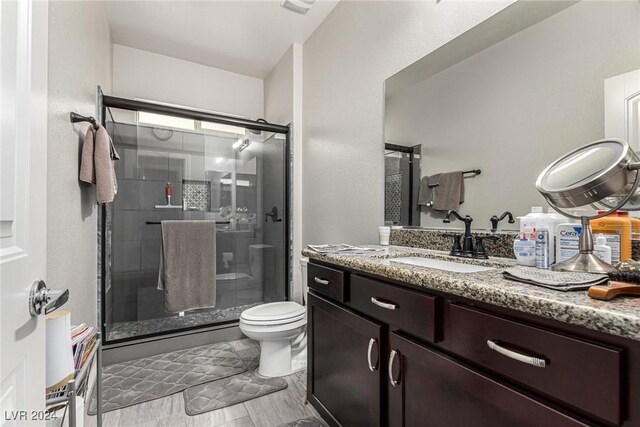 bathroom with vanity, toilet, an enclosed shower, and hardwood / wood-style flooring