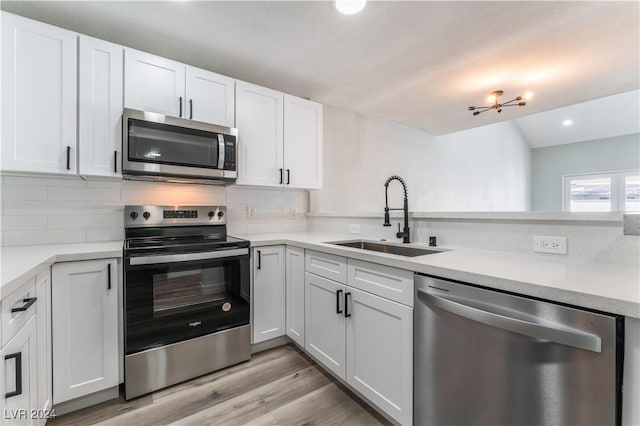 kitchen with white cabinets, appliances with stainless steel finishes, light wood-type flooring, and sink