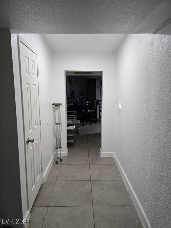 hall with a textured ceiling and tile patterned flooring