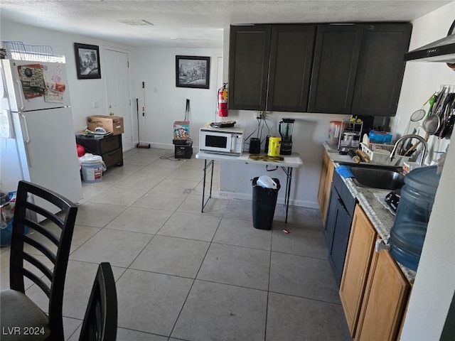 kitchen with white appliances, sink, light tile patterned flooring, and a textured ceiling