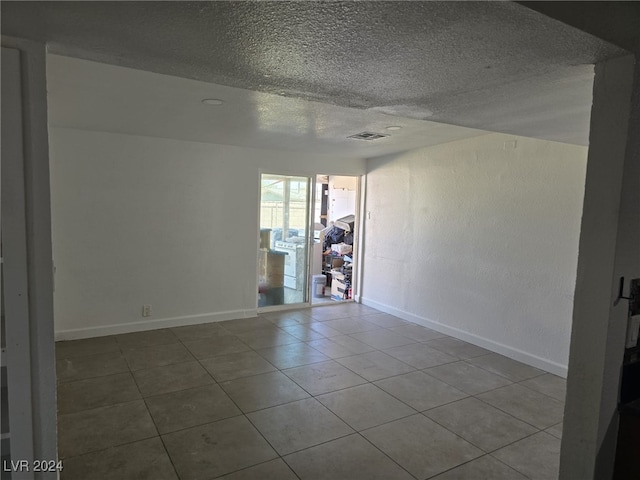 empty room with tile patterned flooring and a textured ceiling