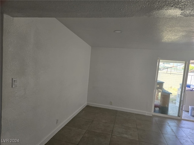 spare room with dark tile patterned flooring and a textured ceiling