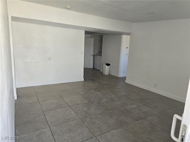 spare room featuring washer and dryer, tile patterned floors, and a textured ceiling