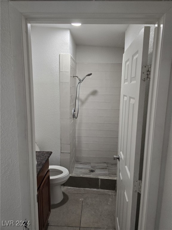 bathroom with vanity, toilet, and tiled shower