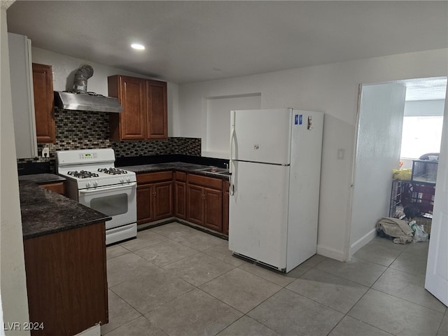 kitchen featuring backsplash, wall chimney range hood, white appliances, and light tile patterned flooring