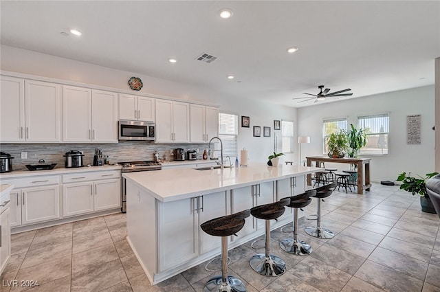 kitchen featuring a center island with sink, ceiling fan, a wealth of natural light, and appliances with stainless steel finishes