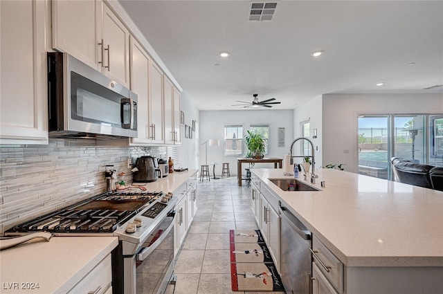 kitchen featuring appliances with stainless steel finishes, plenty of natural light, sink, and a center island with sink