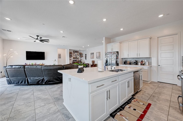 kitchen with a center island with sink, light tile patterned floors, decorative backsplash, white cabinetry, and ceiling fan