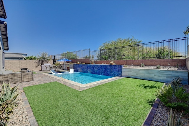 view of swimming pool with pool water feature, a yard, and a patio