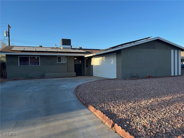 single story home featuring a garage, solar panels, and central AC