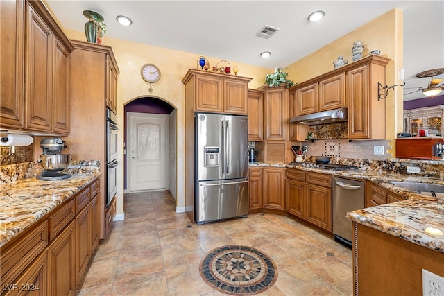 kitchen featuring tasteful backsplash, sink, light stone counters, and stainless steel appliances