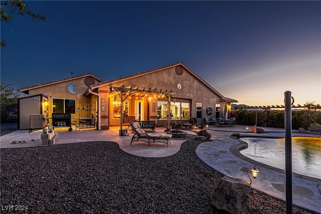 back house at dusk featuring an outdoor fire pit, a pergola, and a patio