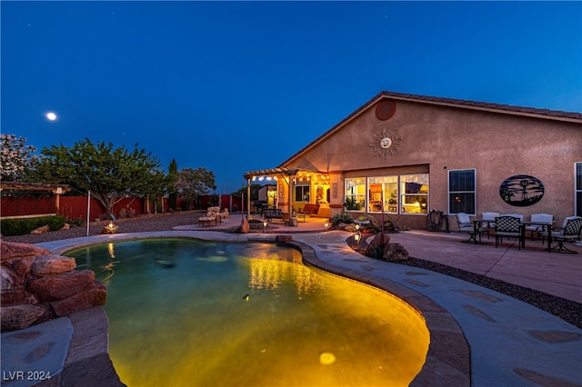 pool at night with a pergola and a patio area