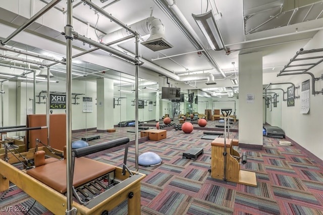 exercise room with carpet floors, visible vents, and a garage