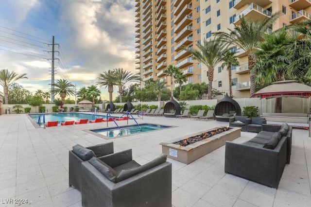 pool featuring a gazebo, a patio area, an outdoor living space with a fire pit, and fence