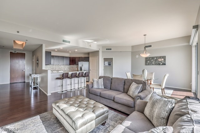 living room with dark wood-style floors, visible vents, and baseboards