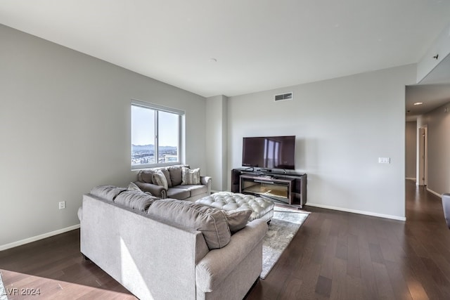 living room with dark wood-style floors, visible vents, and baseboards