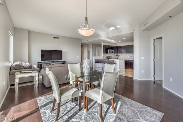 dining space with dark wood-style floors, visible vents, and baseboards