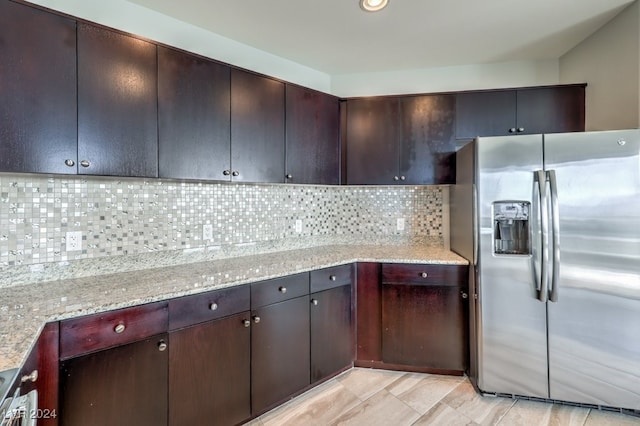 kitchen featuring tasteful backsplash, stainless steel fridge, and light stone countertops