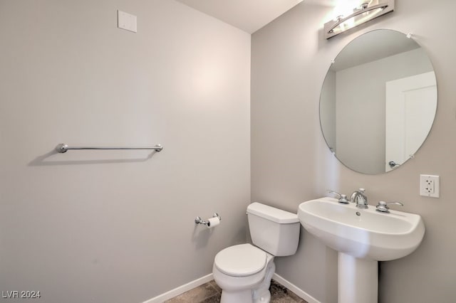 half bathroom featuring a sink, toilet, and baseboards