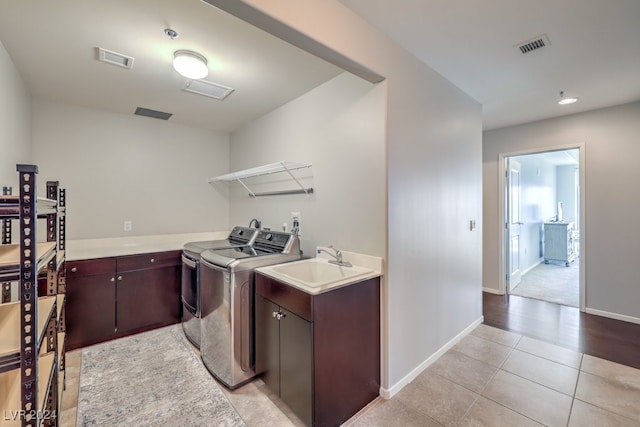 laundry area with cabinets, light tile patterned flooring, separate washer and dryer, and sink