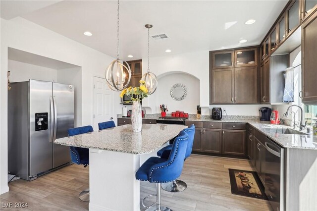 kitchen featuring sink, a center island, a kitchen breakfast bar, light hardwood / wood-style floors, and appliances with stainless steel finishes