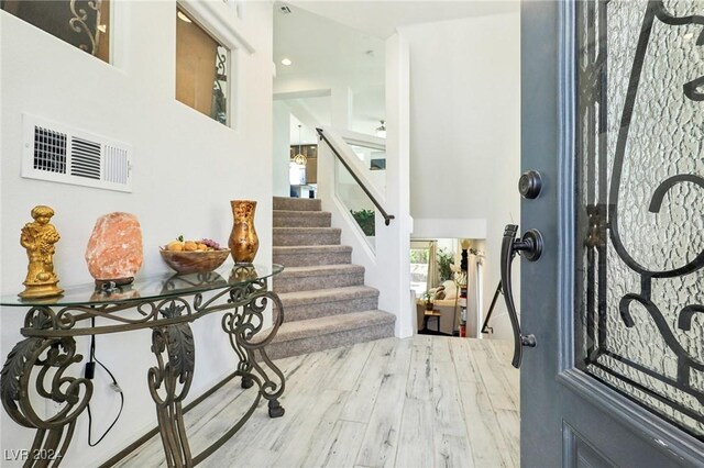 entrance foyer with wood-type flooring and a towering ceiling