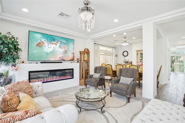 living room with a chandelier, light hardwood / wood-style floors, and crown molding