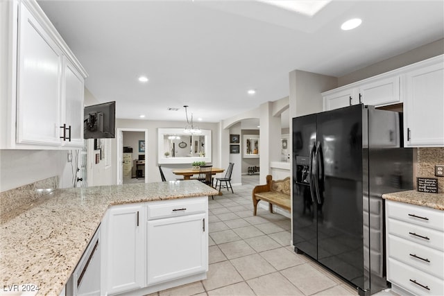 kitchen with light stone countertops, black refrigerator with ice dispenser, pendant lighting, light tile patterned floors, and white cabinetry