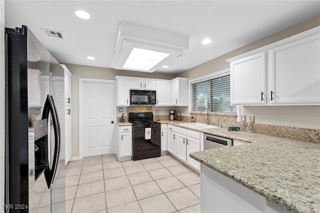 kitchen featuring light stone countertops, sink, black appliances, light tile patterned floors, and white cabinets