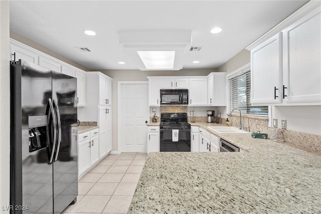 kitchen with black appliances, white cabinets, light stone countertops, and sink