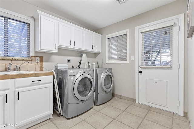 clothes washing area featuring cabinets, independent washer and dryer, light tile patterned floors, and sink