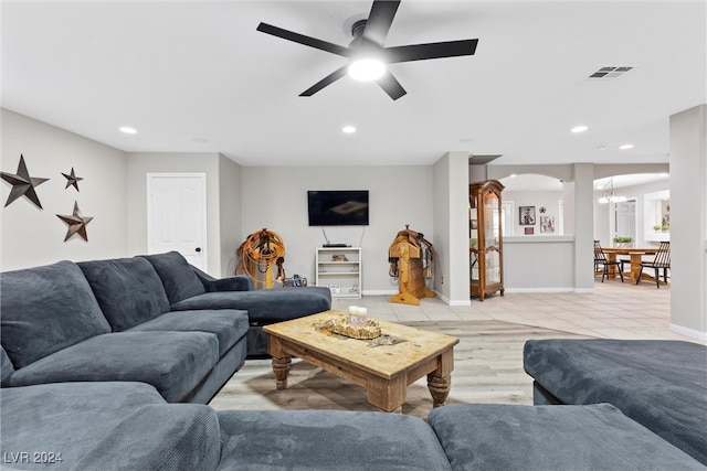 living room with ceiling fan with notable chandelier and light hardwood / wood-style flooring