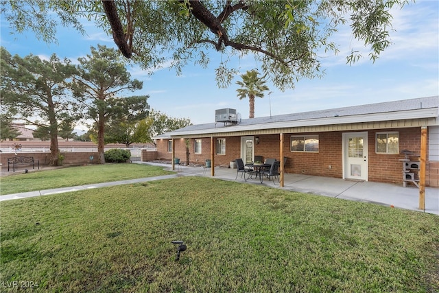 back of house featuring a yard, central AC unit, and a patio area