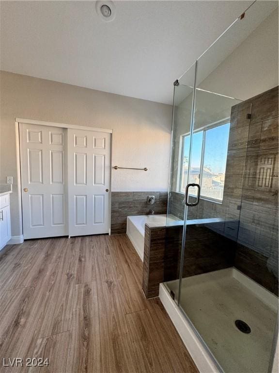 bathroom featuring vanity, wood-type flooring, tile walls, and shower with separate bathtub