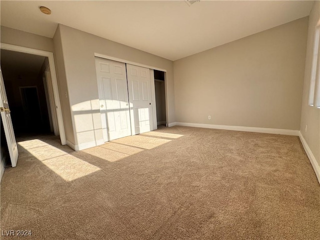 unfurnished bedroom with light carpet and a closet