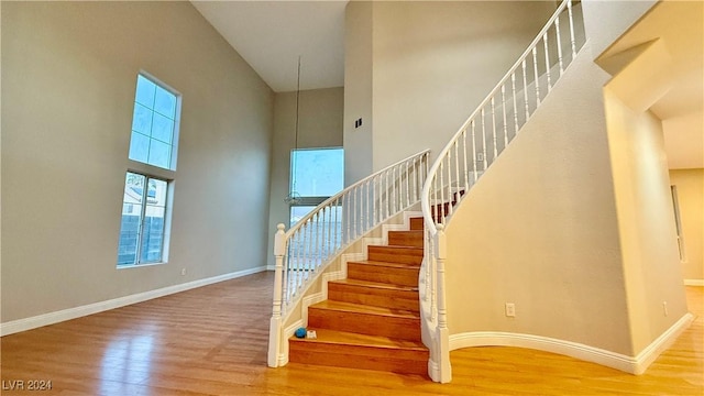 stairway featuring hardwood / wood-style floors and a high ceiling