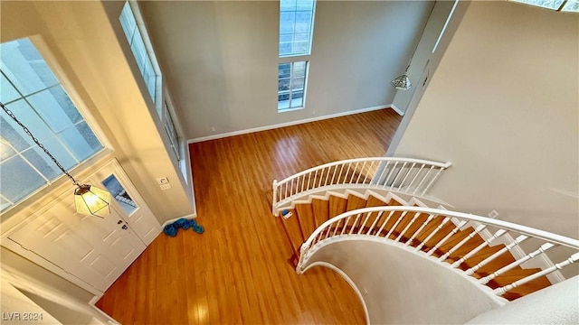 stairs with hardwood / wood-style floors and a towering ceiling