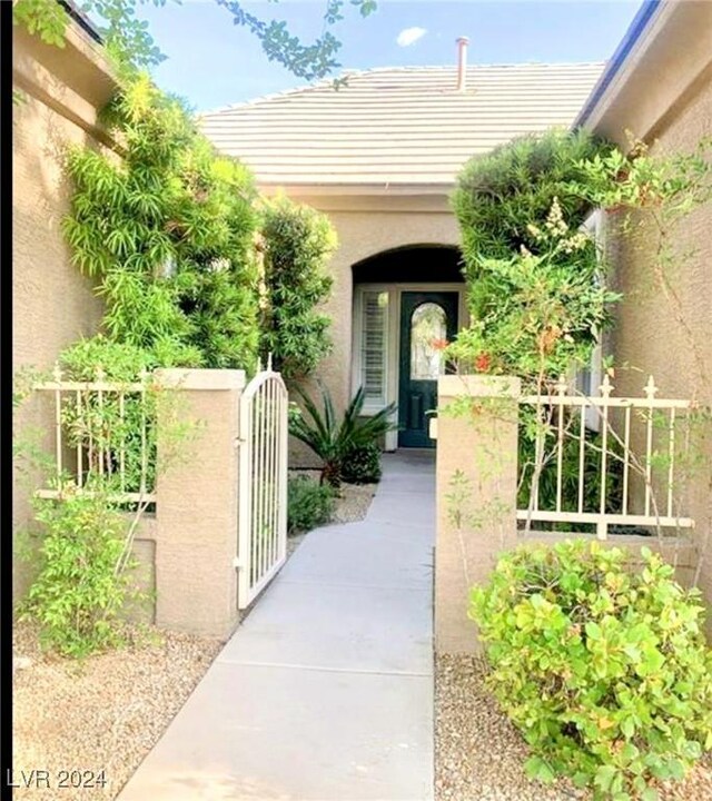 property entrance featuring fence, a gate, and stucco siding