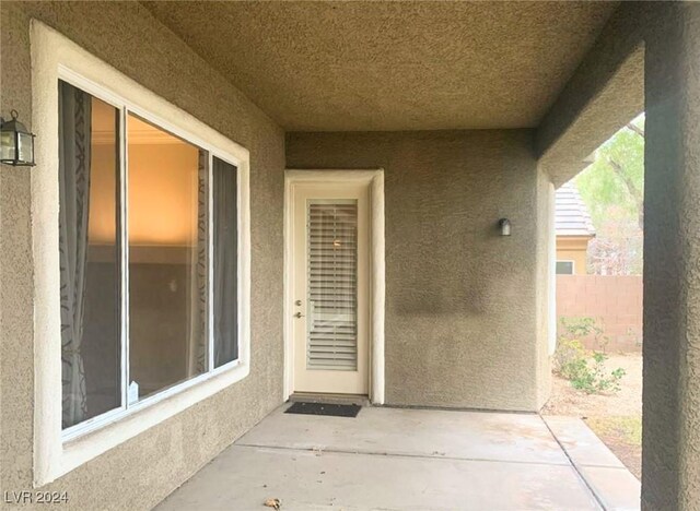 entrance to property featuring a patio area, fence, and stucco siding